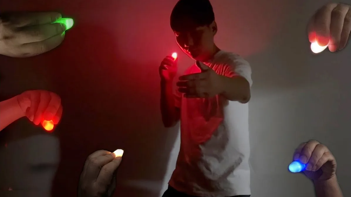 Finger light magic trick: a performer surrounded by Auroshoot thumb lights in five colors